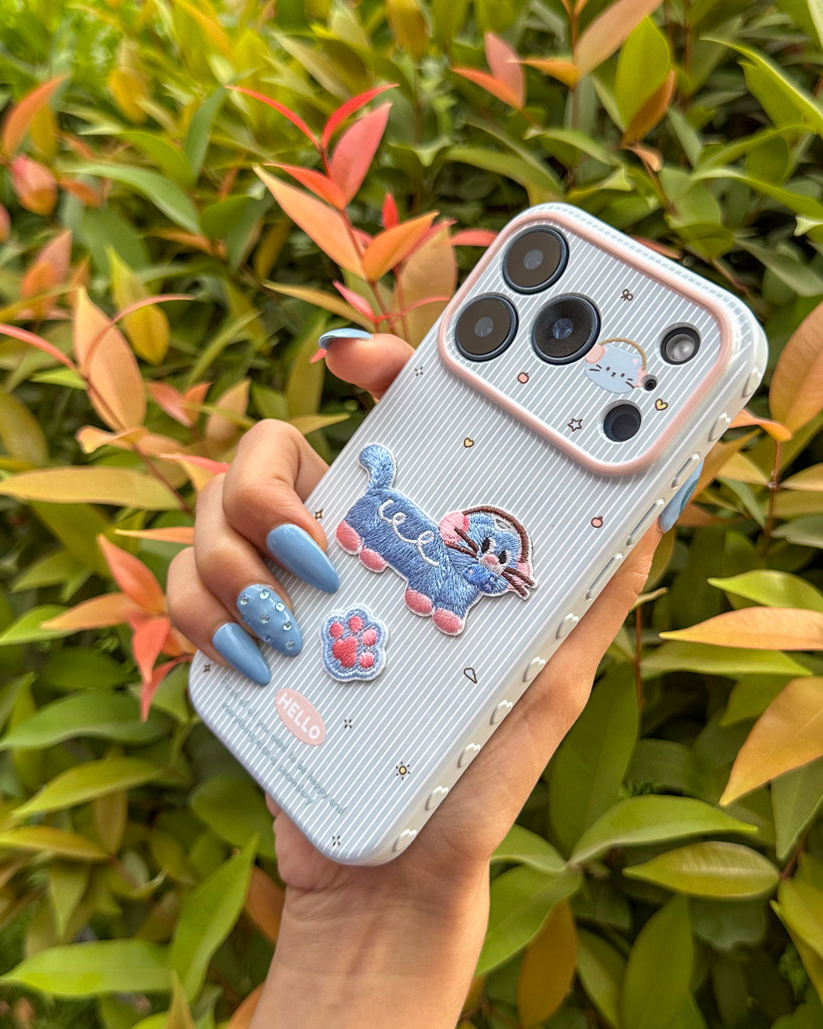 TOKFO Hello Cat phone case held at an angle showing the pink camera ring and embroidered cat