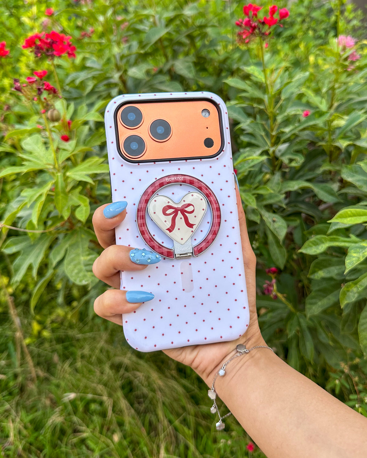 TOKFO Polka Dot Bow Stand iPhone phone case with polka dot print and magnetic heart-shaped kickstand, held in hand