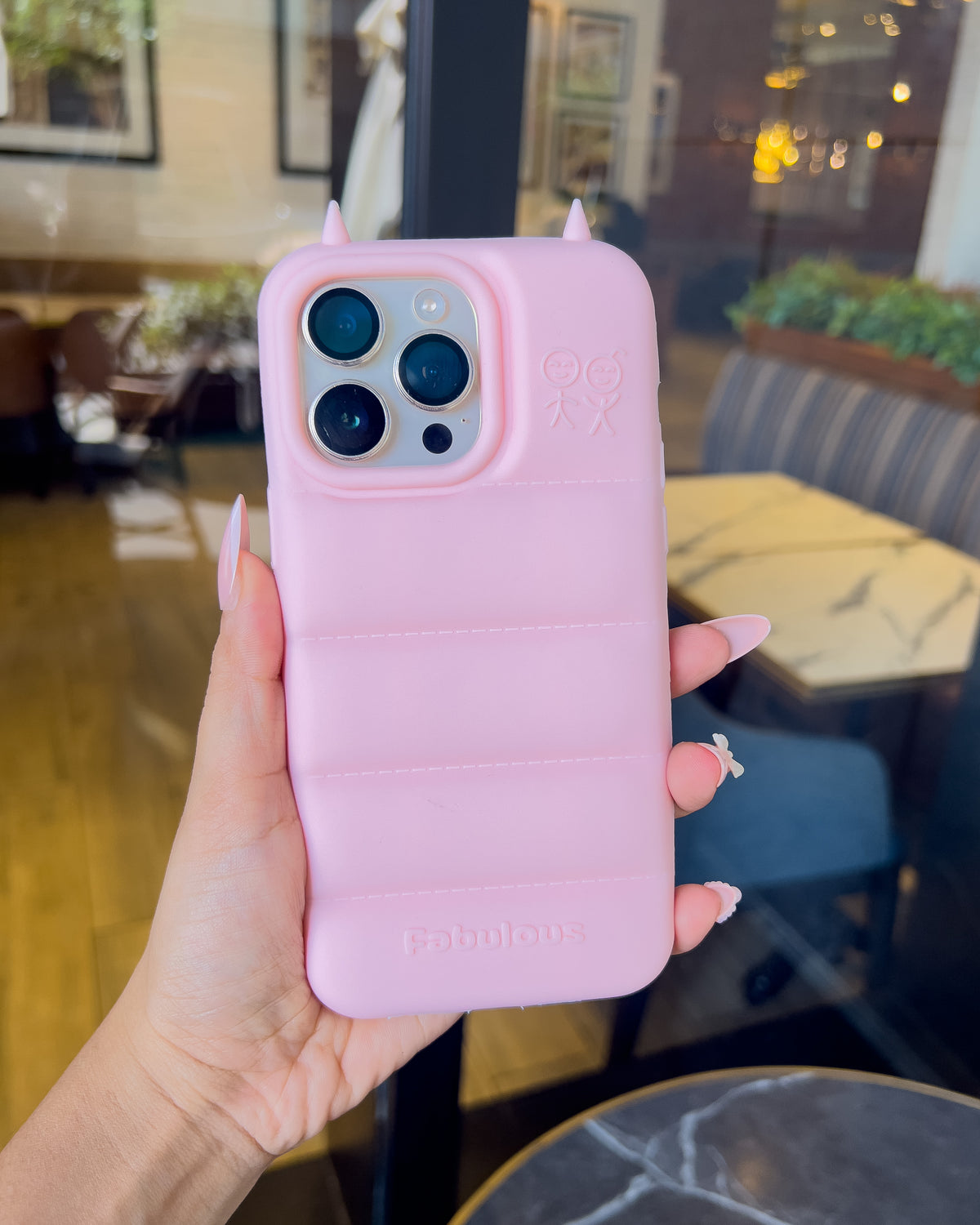 Light pink TOKFO Puffer Devil Horn puffy silicone iPhone phone case with 3D devil horns, held in hand