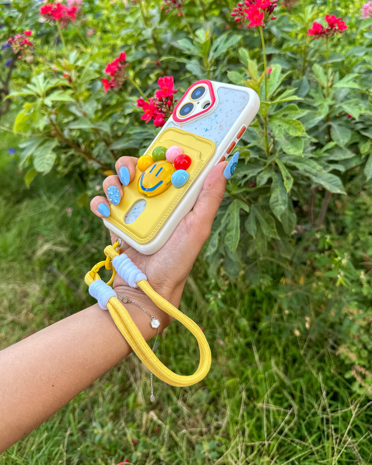 TOKFO Smiley phone case with paint-splatter print back and yellow wrist strap around the wrist