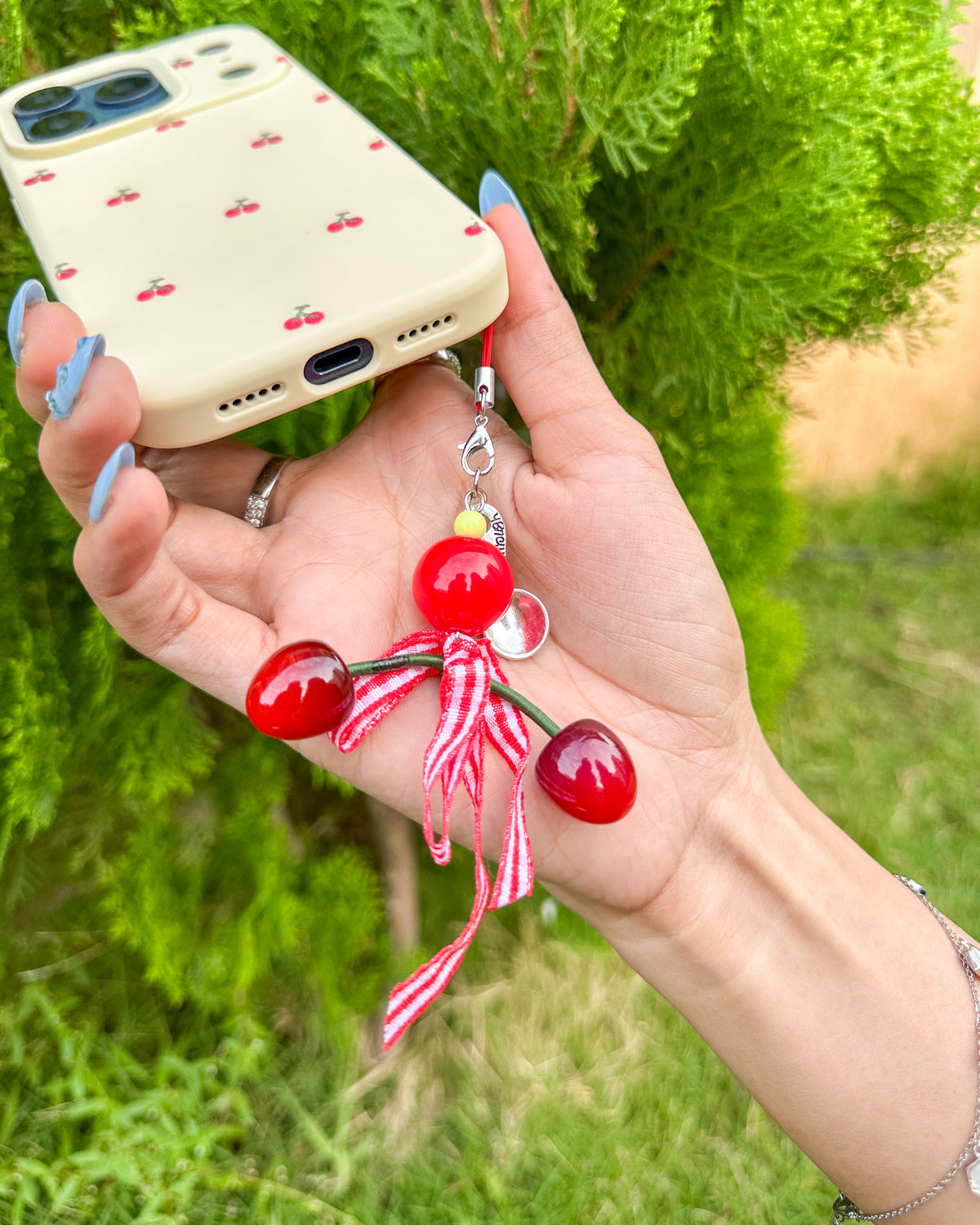 Close-up of the cherry charm with red gingham bow on the TOKFO Cherry phone case