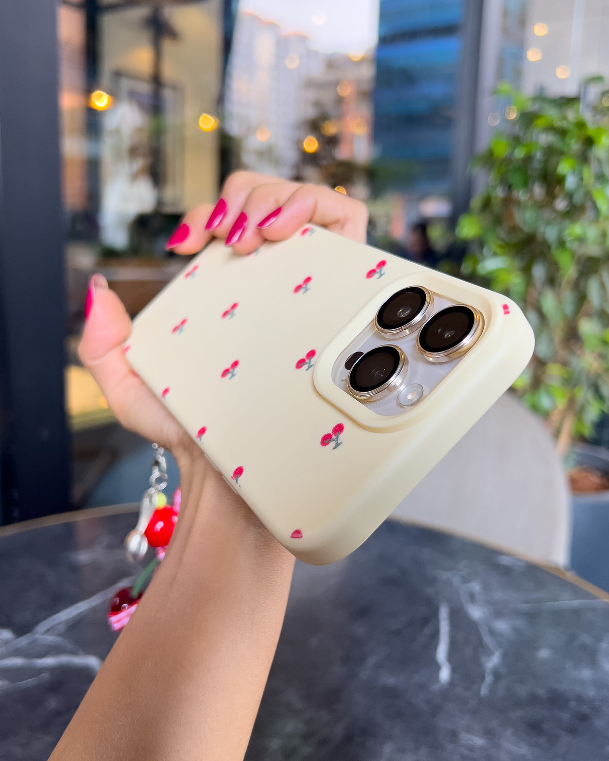 TOKFO Cherry phone case held at an angle showing the raised camera edges and cherry charm