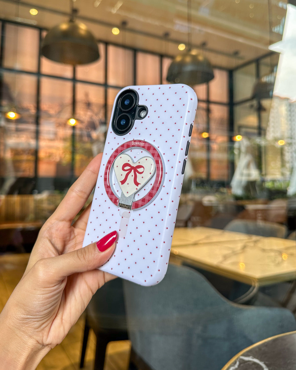TOKFO Polka Dot Bow Stand iPhone phone case with the magnetic heart-shaped kickstand attached, held in hand
