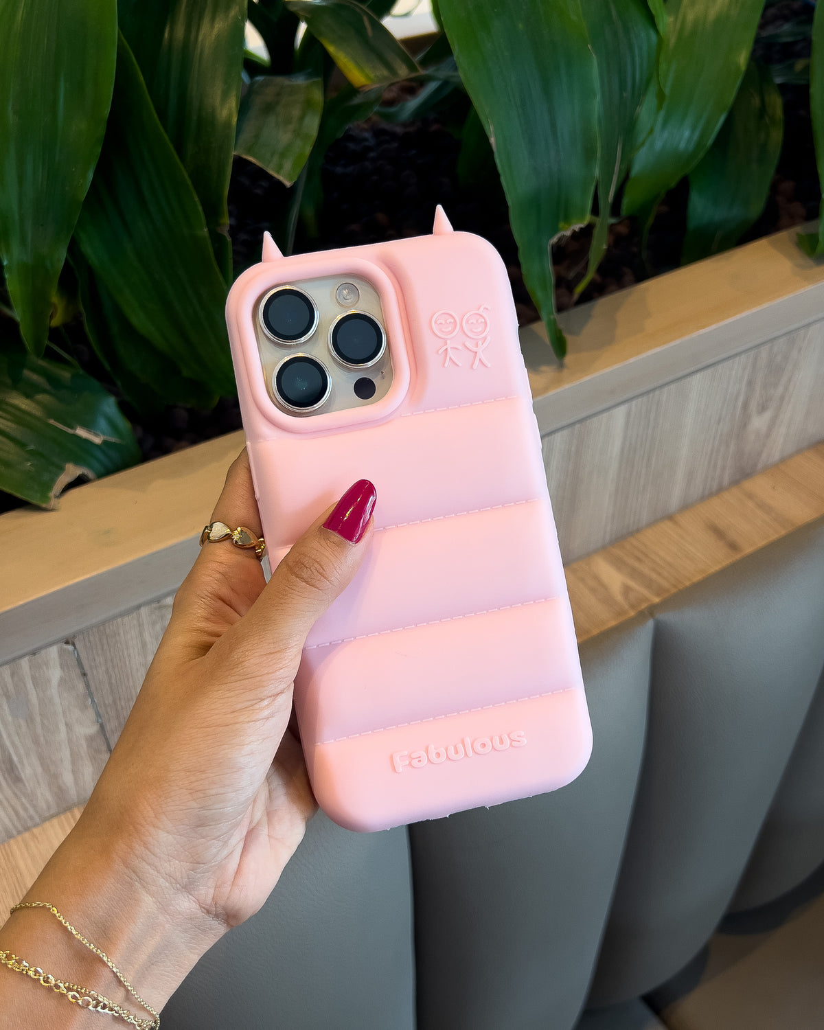 Light pink TOKFO Puffer Devil Horn phone case held in hand outdoors