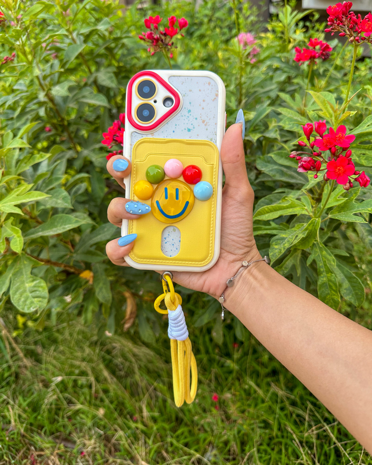 TOKFO Smiley iPhone phone case with 3D smiley face, colourful ball details and wrist strap, held in hand