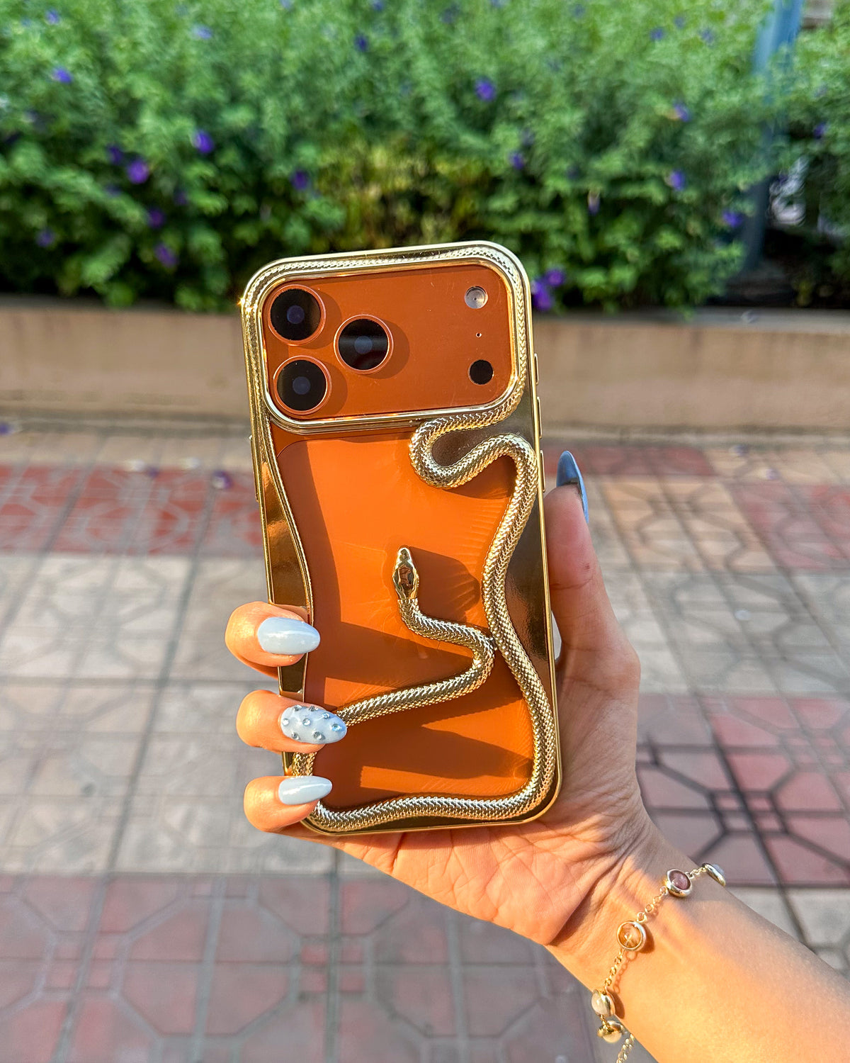 TOKFO Snake open-back iPhone bumper phone case with bold 3D golden snake design on an orange iPhone, held in hand