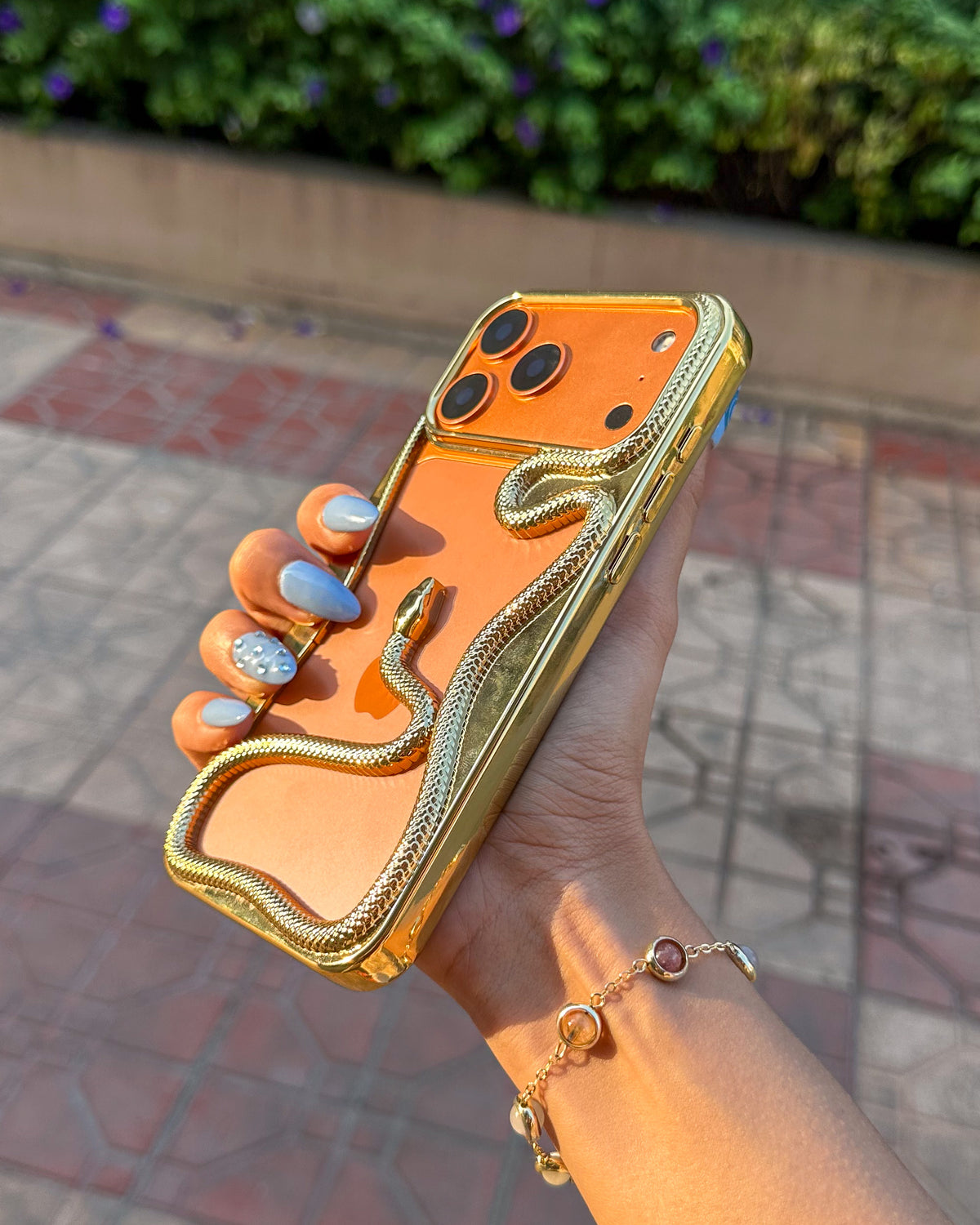 Golden TOKFO Snake phone case held at an angle showing the raised camera edges and 3D snake